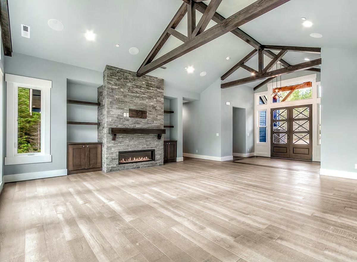 Stone Fireplace Wall and Beam Trusses Anchor an Unfurnished Great Room