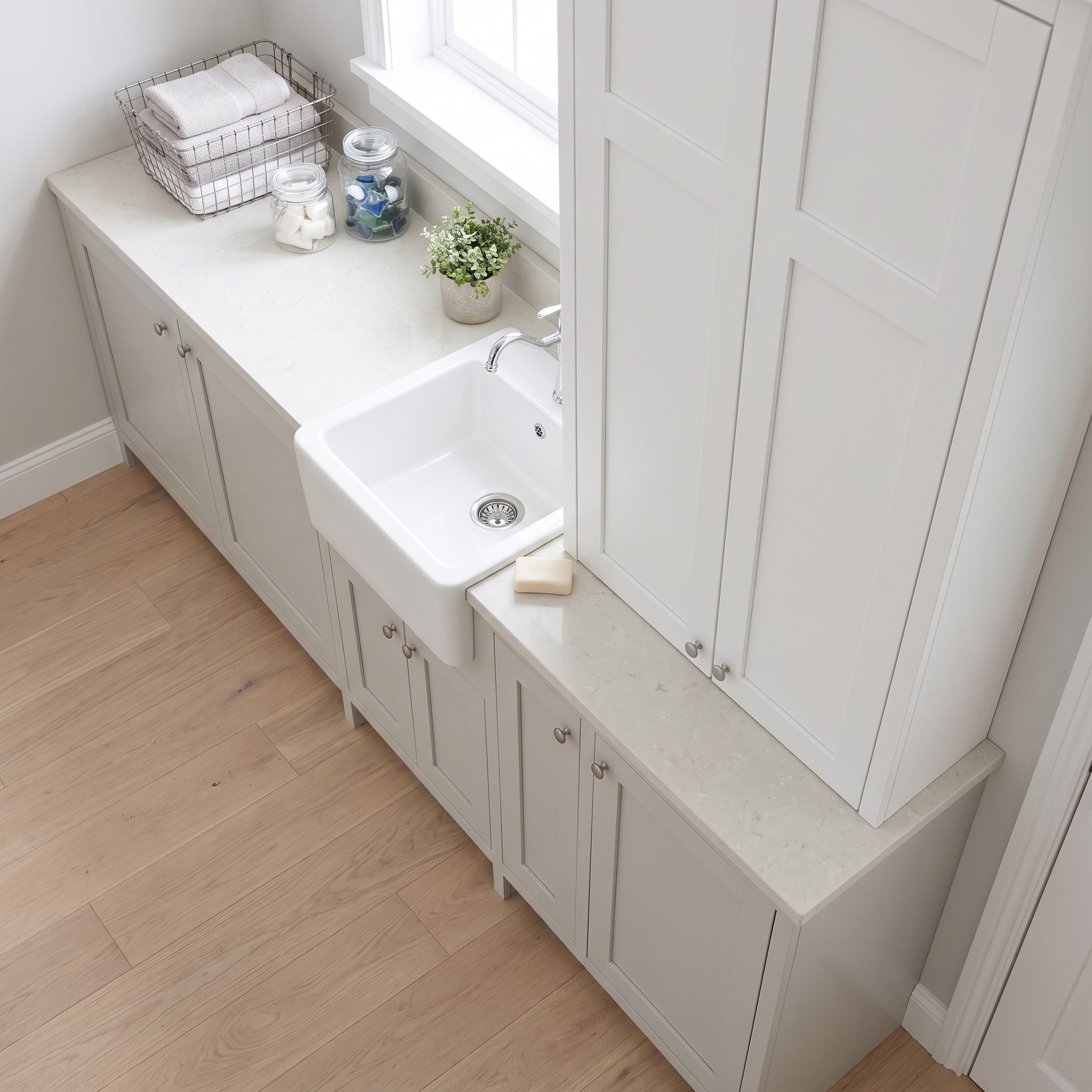 Gray-green laundry room where a sink and jutting cabinet chop the folding counter into two short segments.