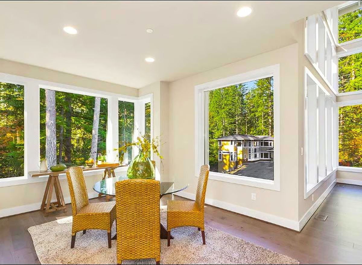 Wicker Chairs and a Glass Table Turn a Forest View Into a Daily Ritual