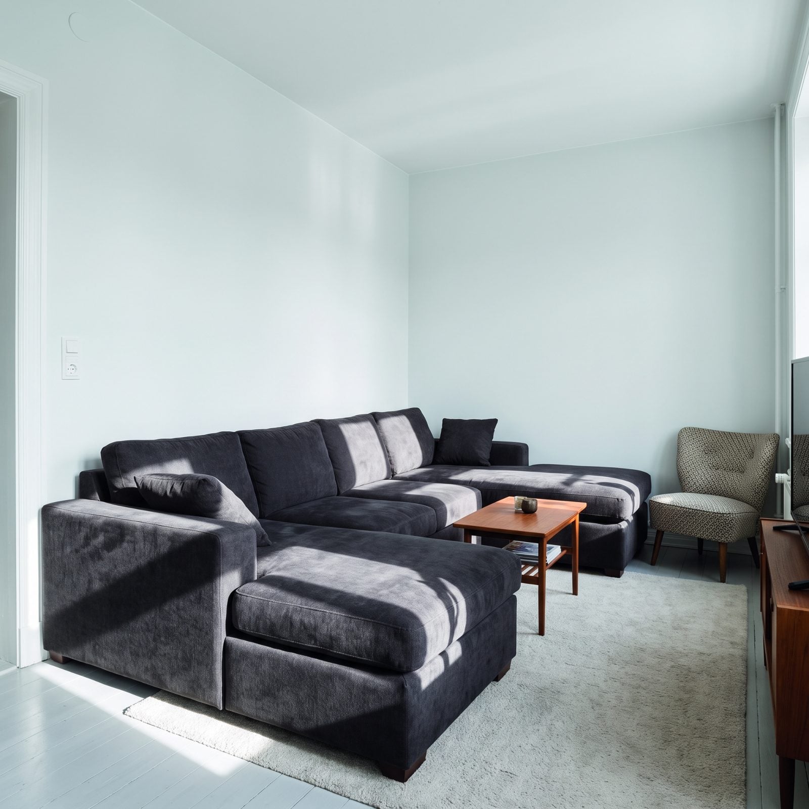 A Charcoal Sofa Dominating a Small, Pale Room