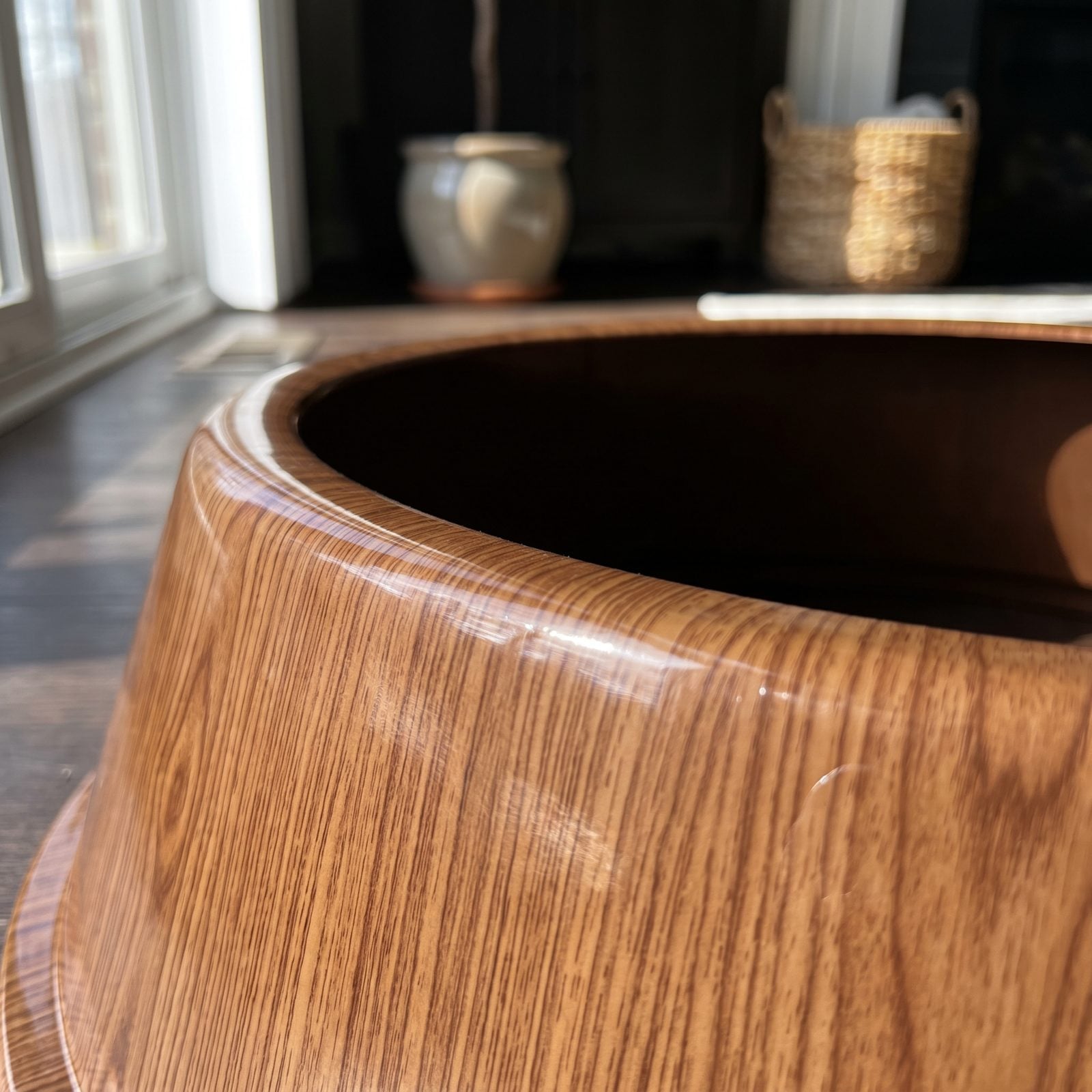 Artificial tree base wrapped in a shiny plastic collar printed with a repeating faux wood-grain pattern and a visible seam.