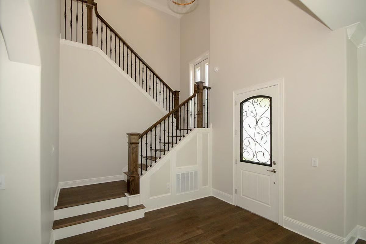 Wrought Iron Balusters and Dark Wood Treads Set the Tone at the Front Door
