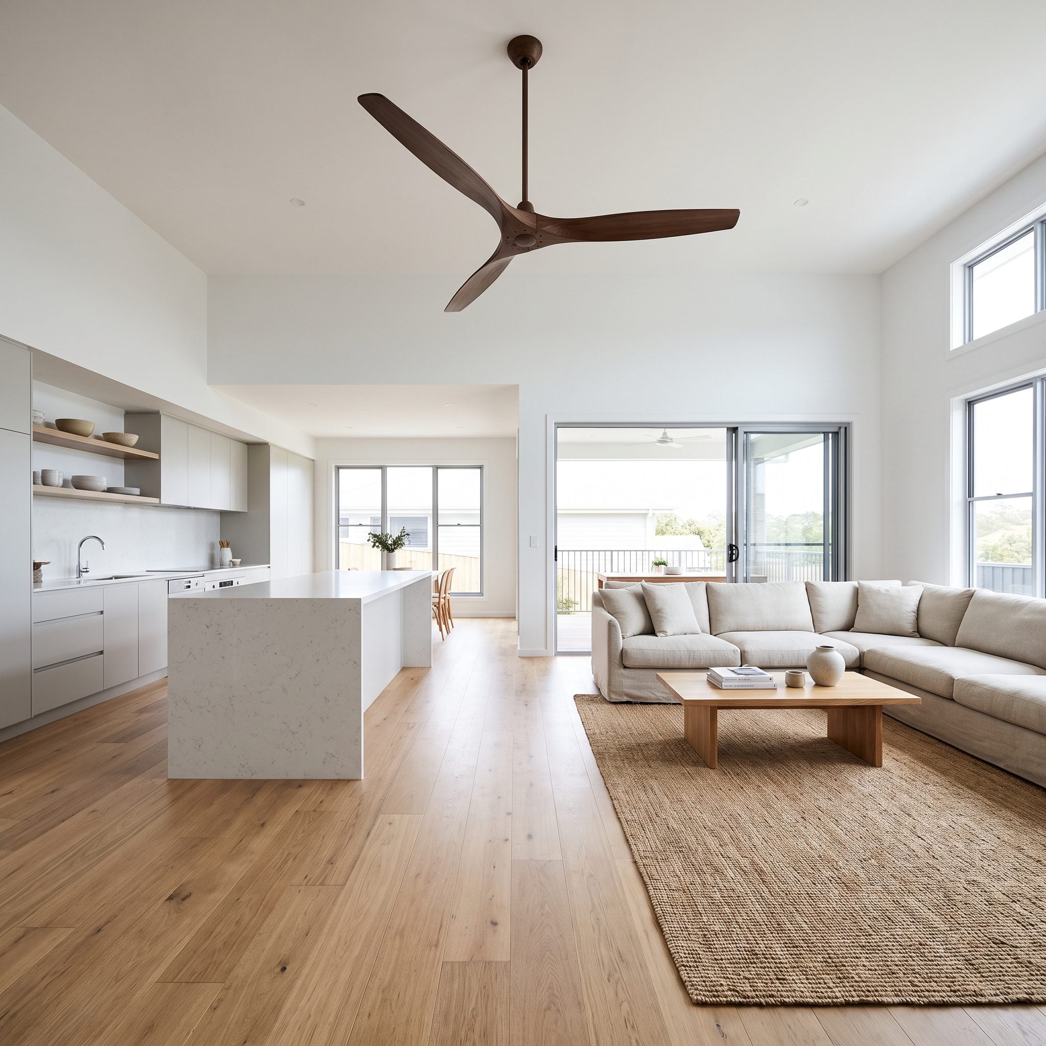 Open-plan kitchen and living area with one 66-inch matte-black ceiling fan centered over the boundary between the island and