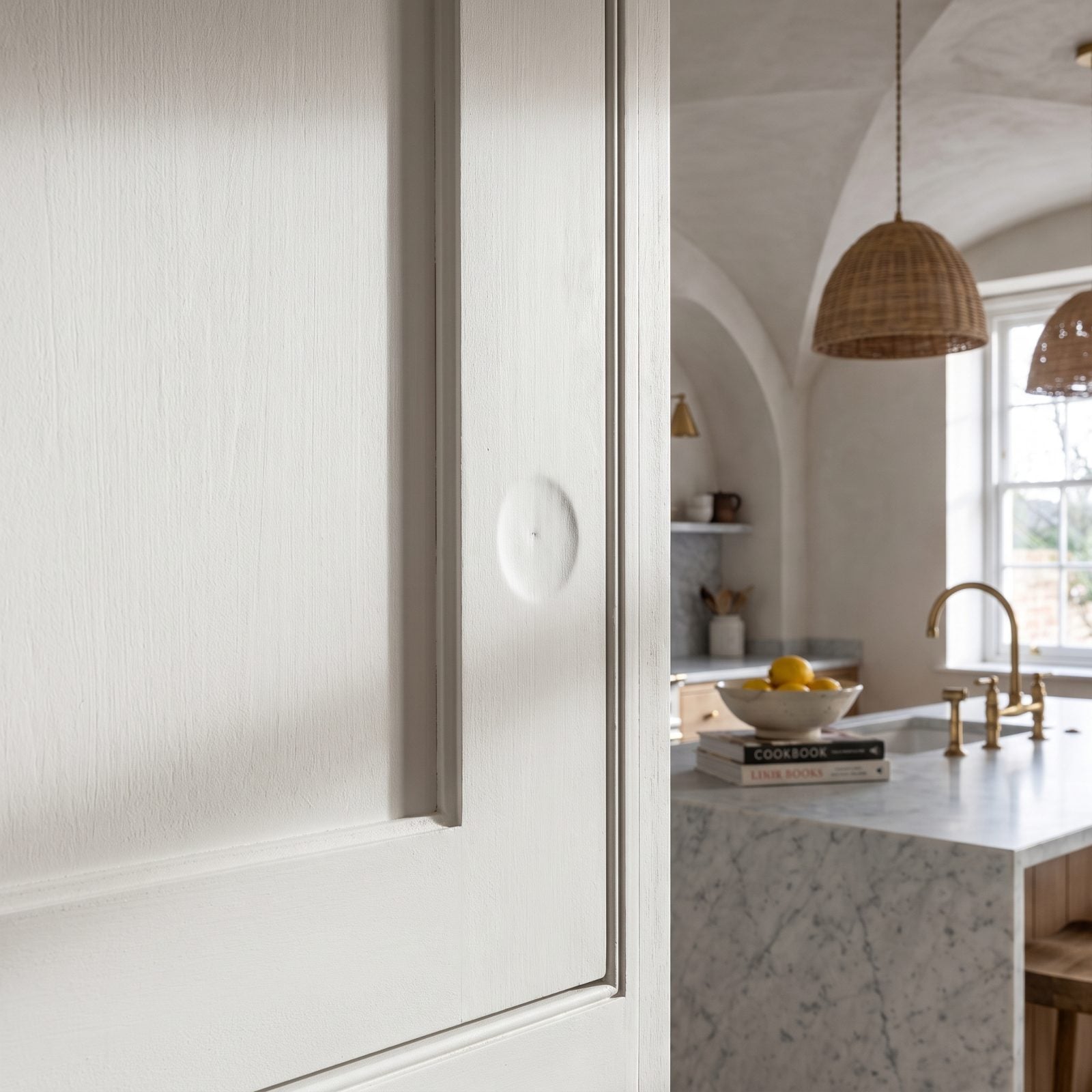 White cabinet door with a filled former handle hole showing as a faint sunken ring under the paint next to a new pull.