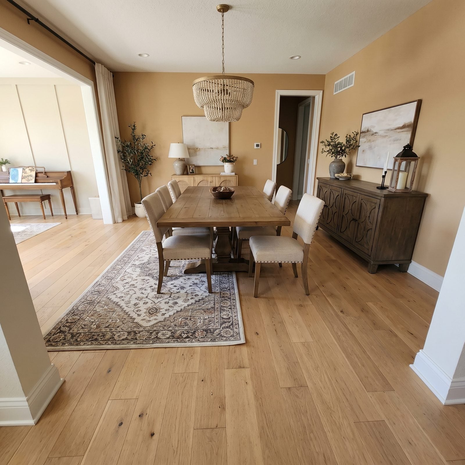 Open-plan dining area where the rug under the walnut table is too small, leaving chair back legs and pulled-out chairs on