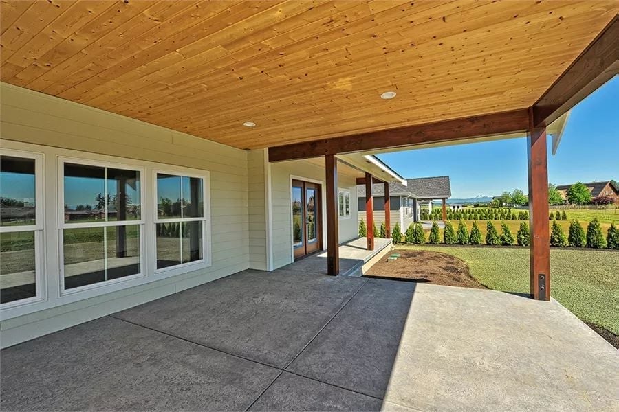 Cedar-Clad Ceiling and Dark Wood Posts Define a Covered Patio Built for Rural Views