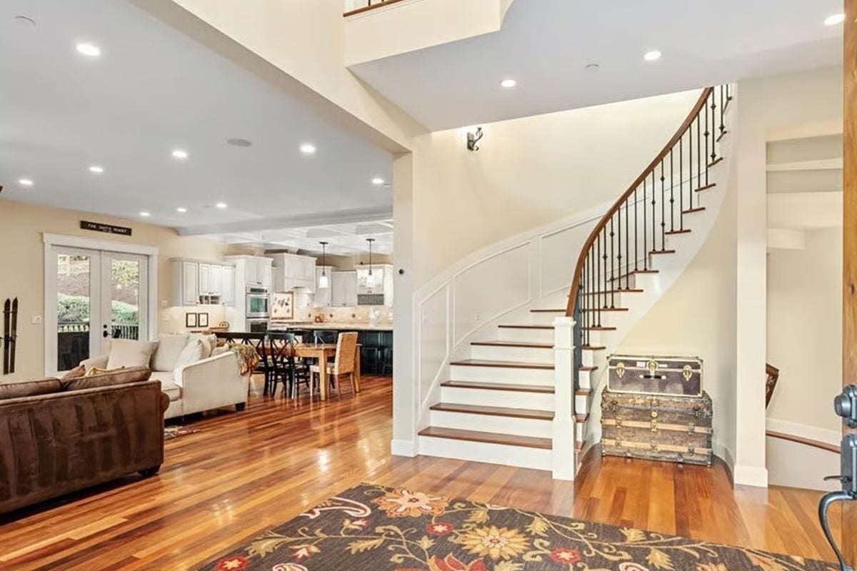 Curved Staircase With Iron Balusters Does the Heavy Lifting in This Entry
