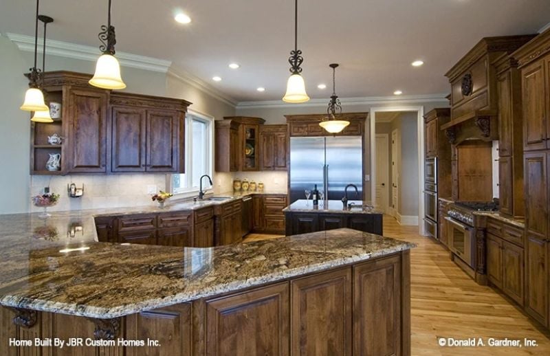 Granite Islands and Ironwork Pendants Define a Kitchen Built Around Serious Cooking