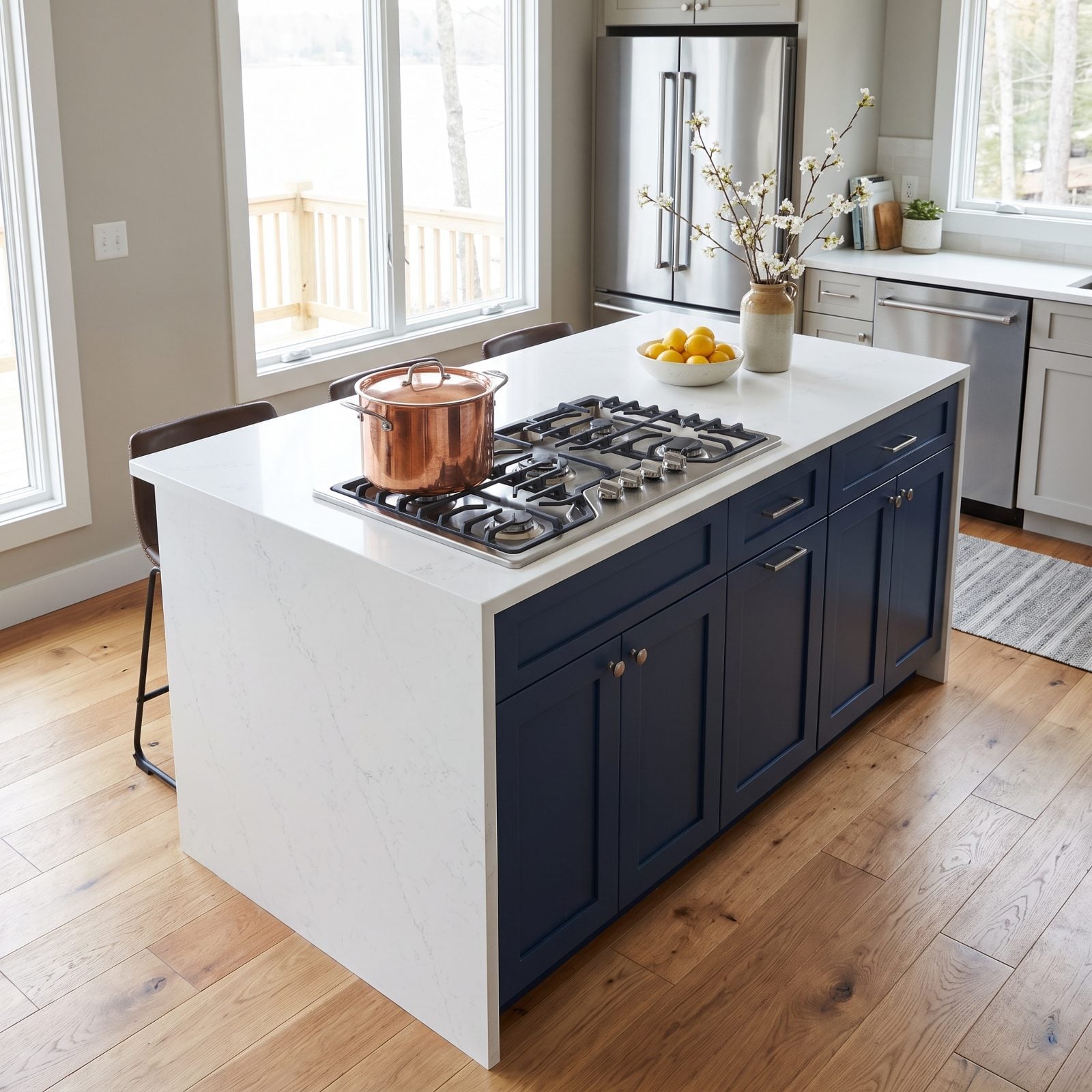 Navy waterfall island with a gas cooktop set close to the front edge, leaving only about eight inches of landing space to a