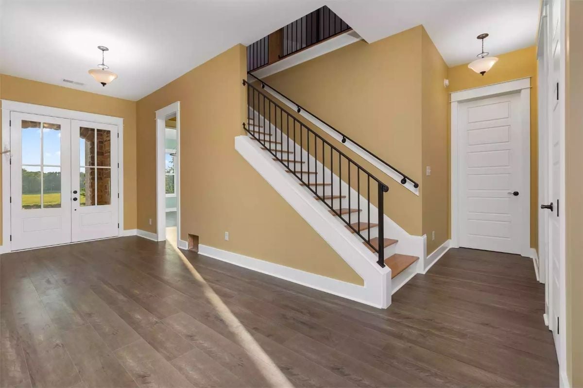 Warm Wheat Walls and Iron Railings Make This Foyer Worth Coming Home To