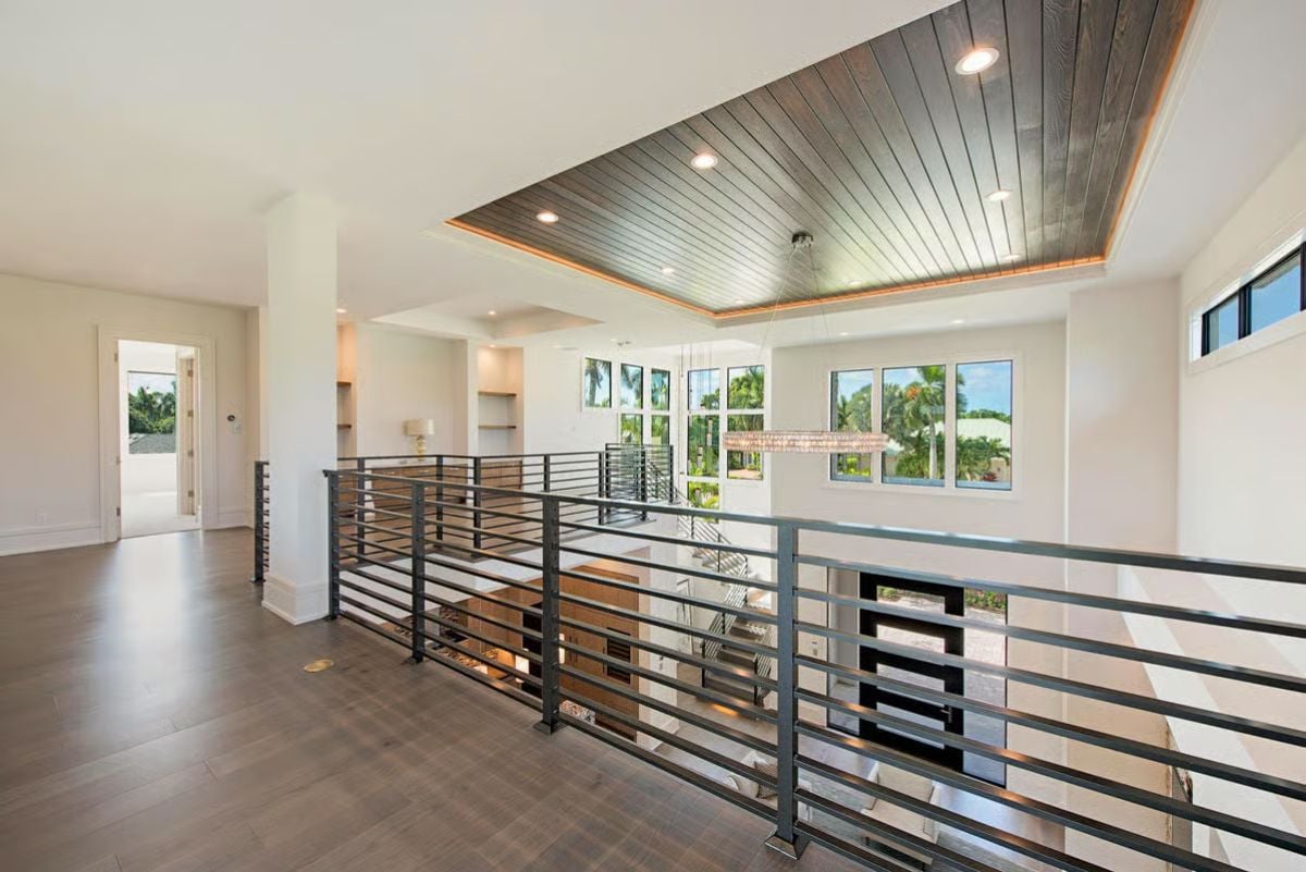 Dark Wood Ceiling Inset and Horizontal Rails Define This Upper-Level Hallway