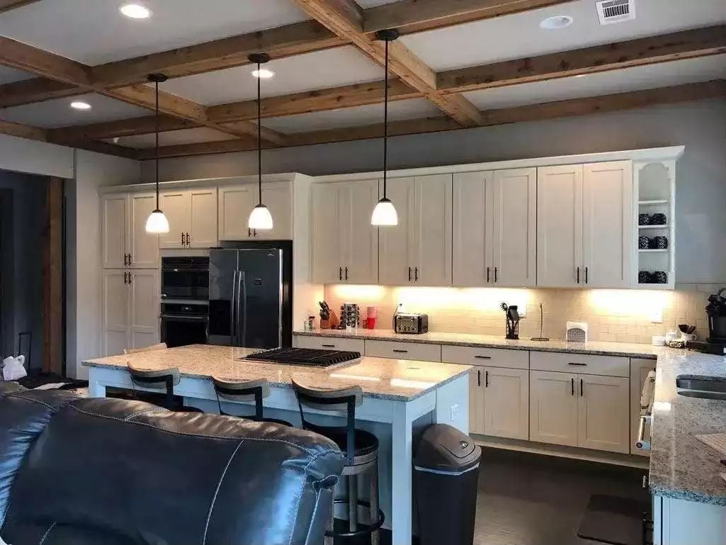 Exposed Ceiling Beams Do the Heavy Lifting While White Cabinets Keep Things Grounded