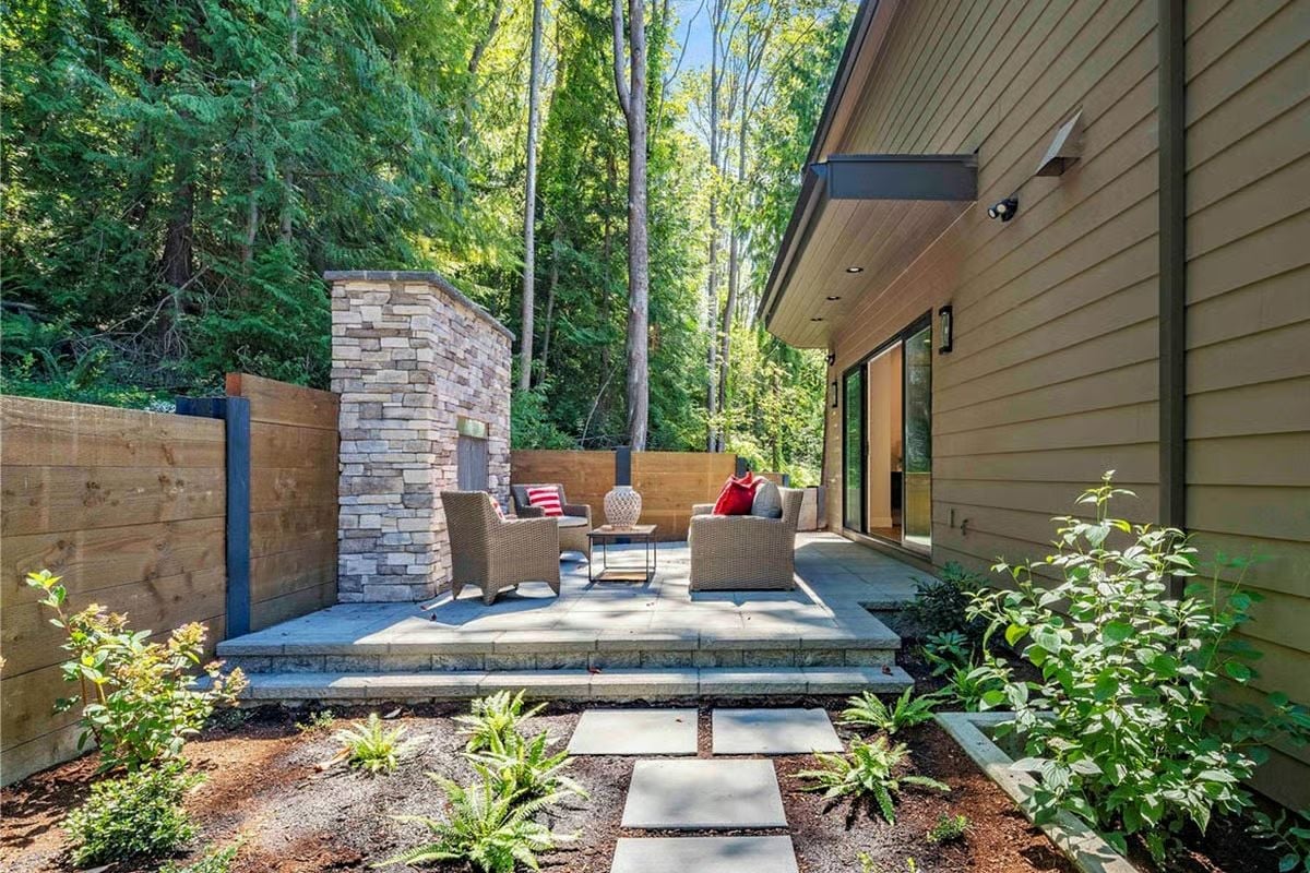 Stone Fireplace Column and Wicker Seating Carved Out of a Wooded Side Yard