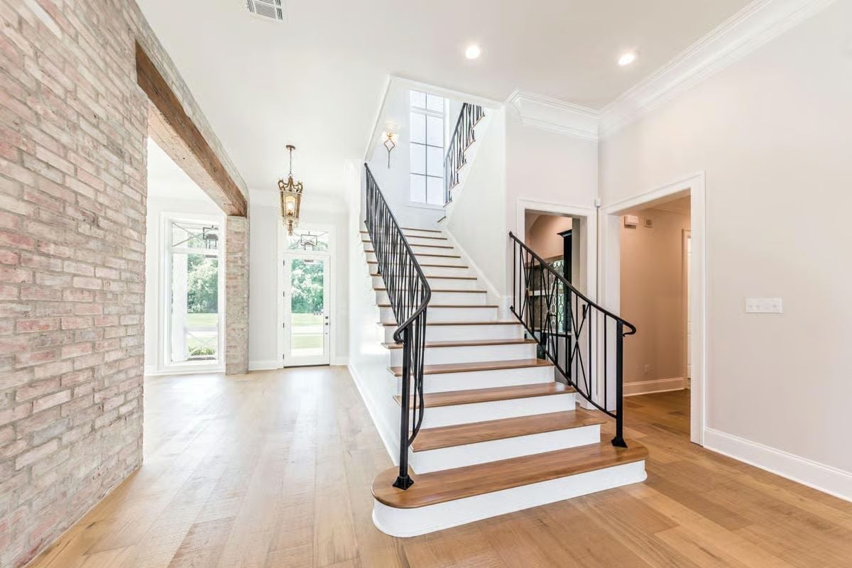 Exposed Brick Arch and Iron Stair Rail Give This Foyer Its Whole Personality