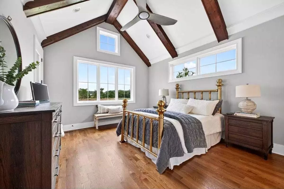 Brass Bed Frame and Exposed Beams Pull This Vaulted Bedroom Into Its Own Era