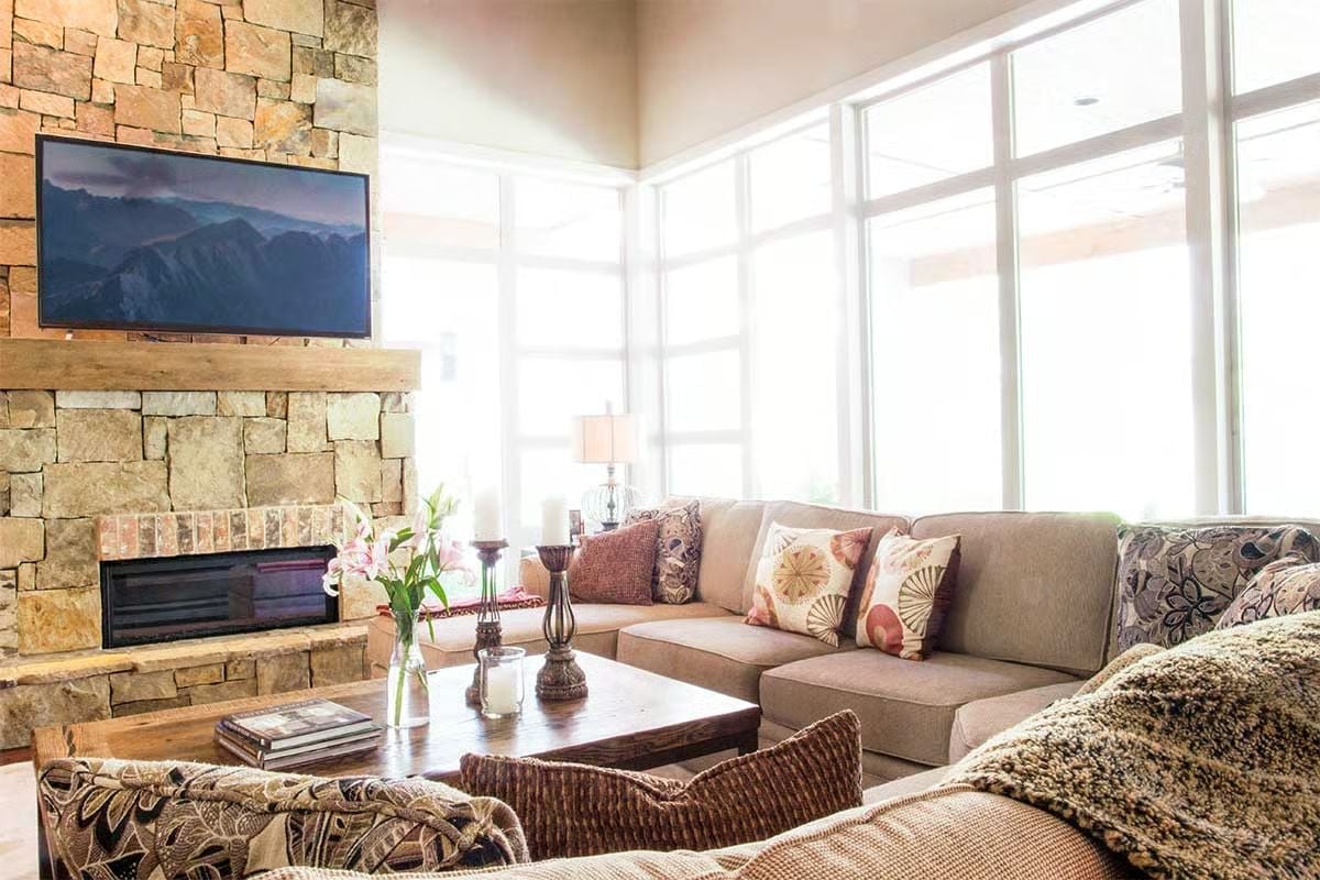 Stone Wall, Wood Mantel, Mountain on the Screen — Living Room Gets It Right