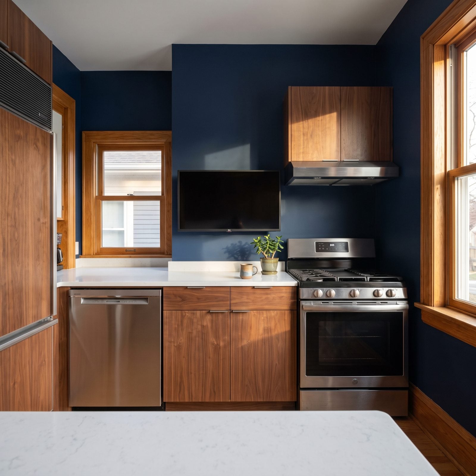 Walnut modern kitchen with a 43-inch television mounted low above a short counter run, blocking usable prep space beneath it.