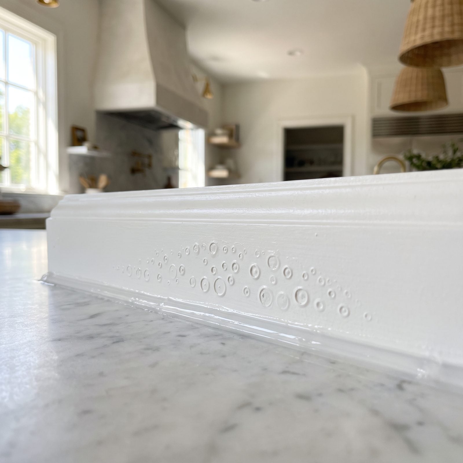 Cabinet seam where fresh paint beads and cracks off a strip of silicone caulk.