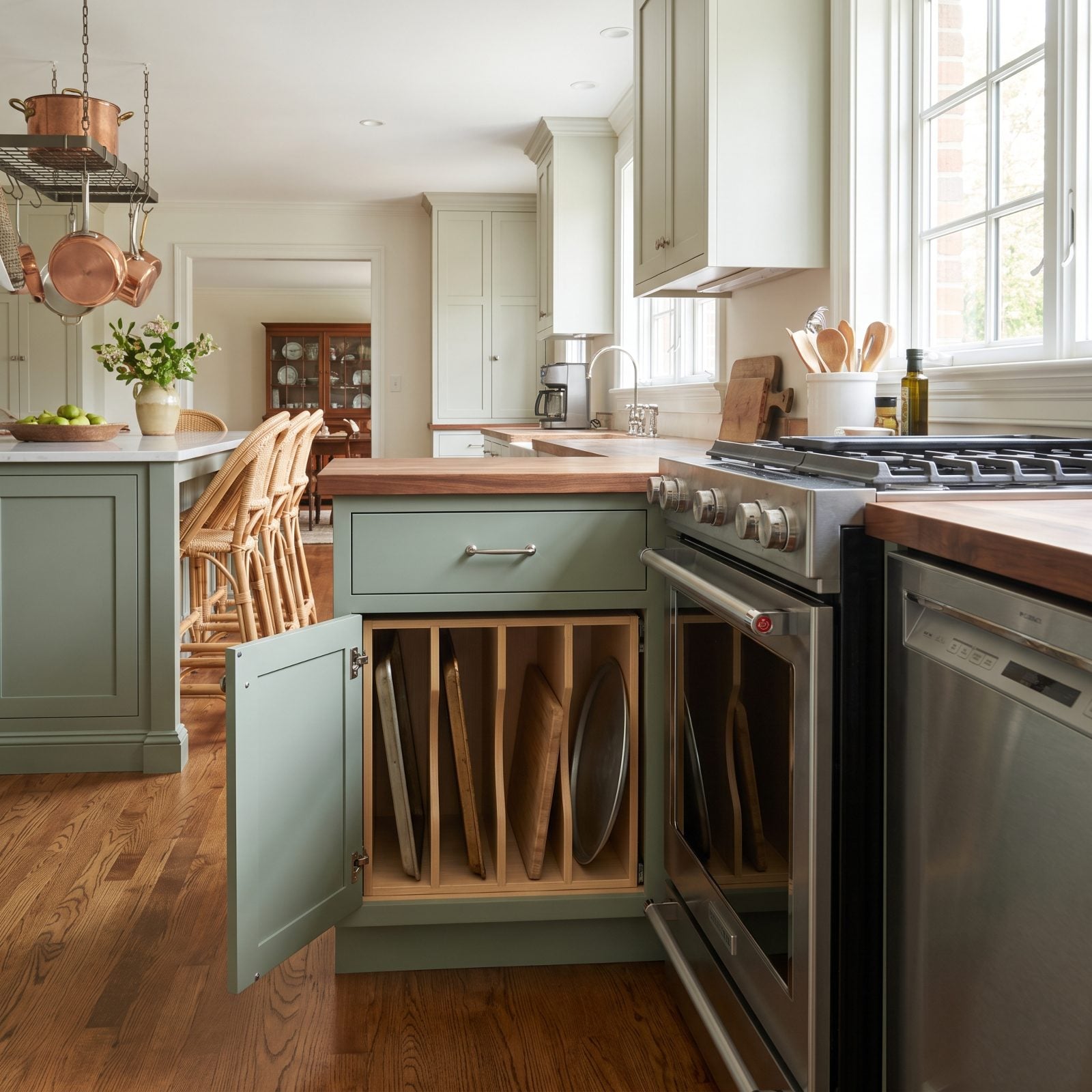 Sage green kitchen with a base cabinet full of vertical tray dividers holding a few baking sheets.