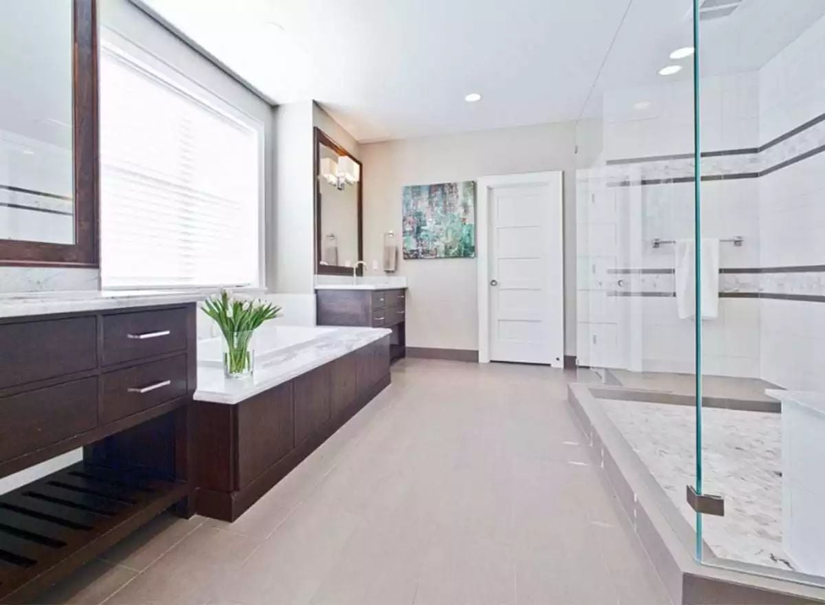 Marble Tub Surround and Glass Shower Wall Split This Bathroom Into Two Worlds