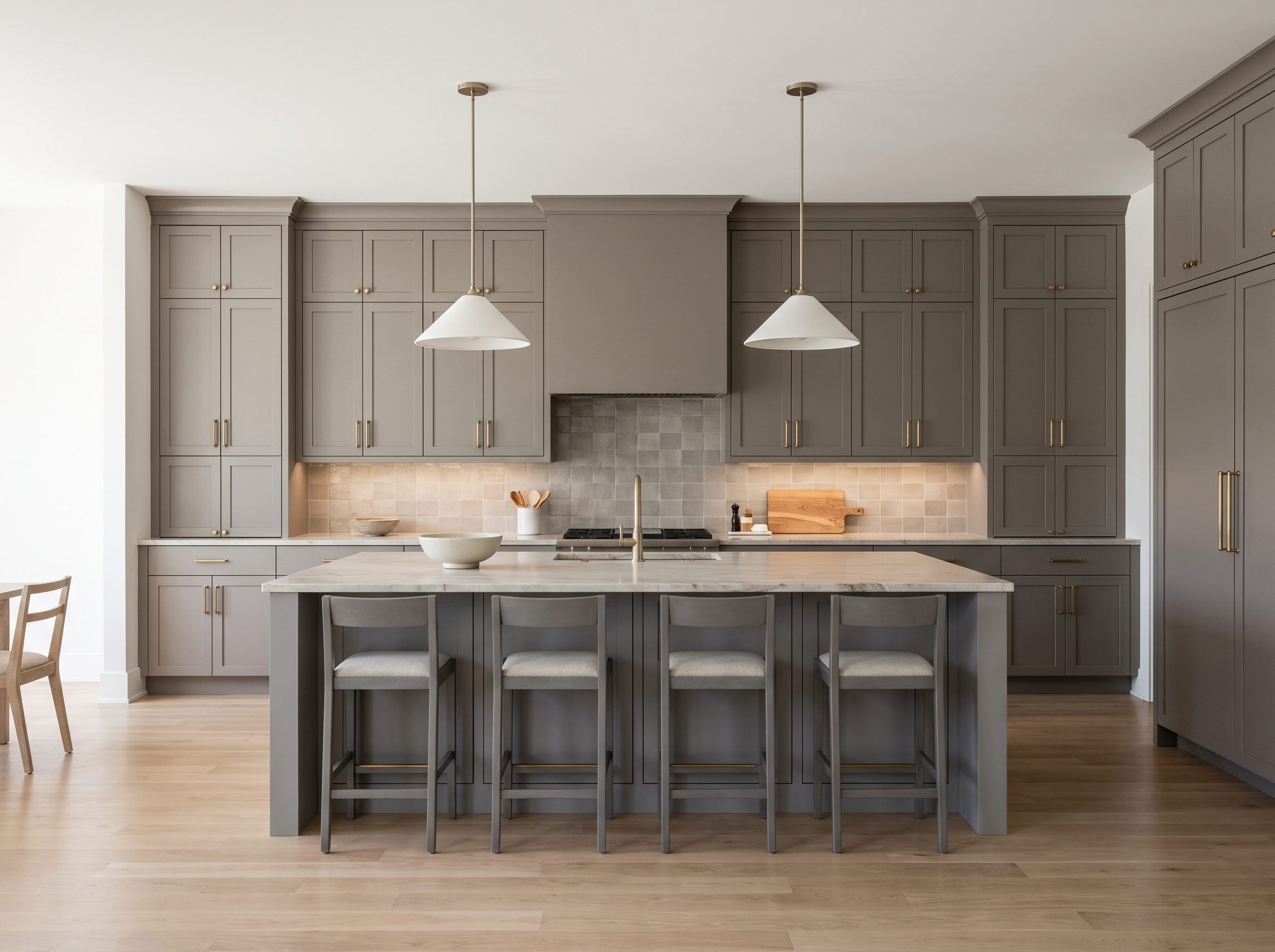 Contemporary kitchen with warm-gray cabinetry along the back wall, an eight-foot gray island with three stools, white-oak