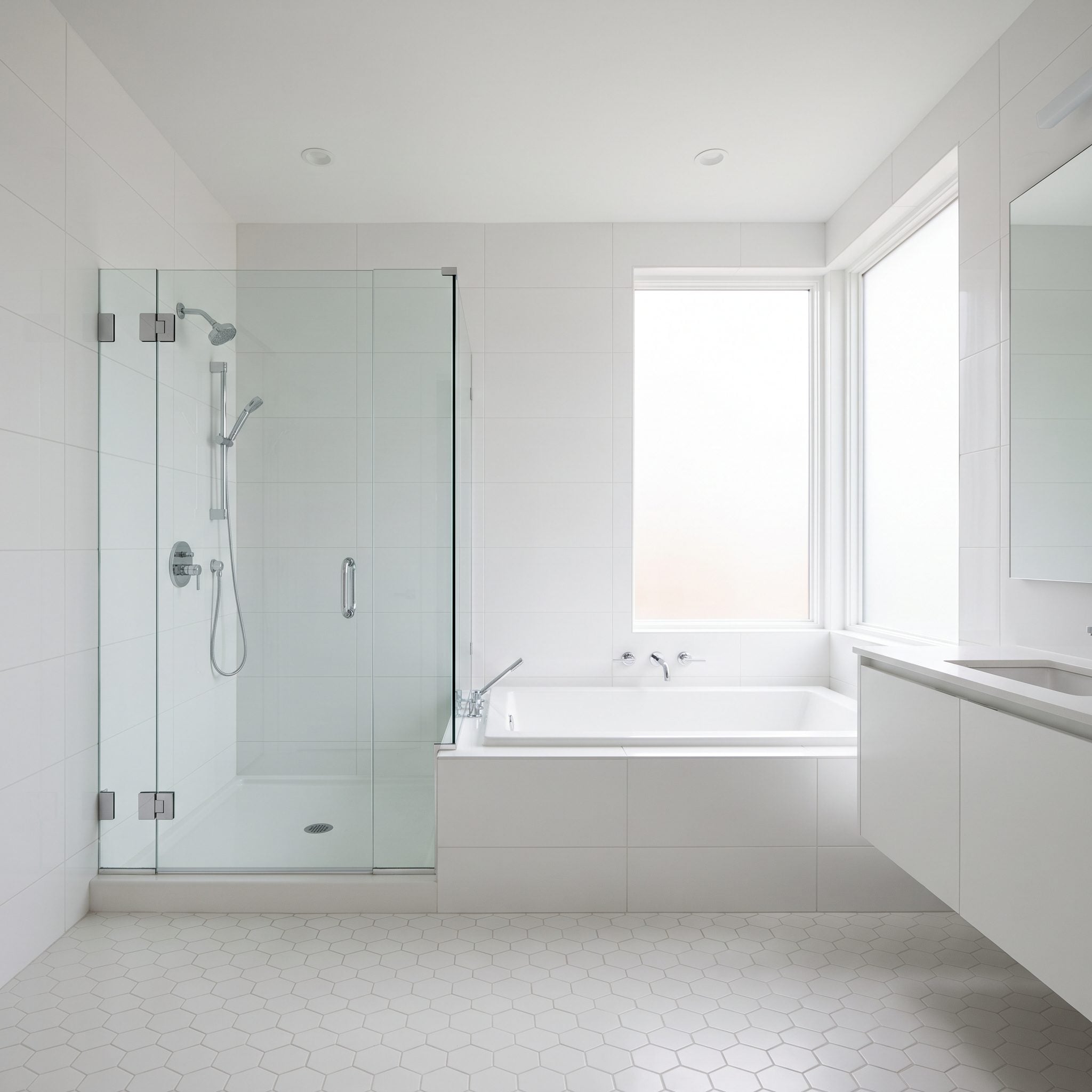 Bathroom with a freestanding tub beside a glass walk-in shower sharing one tiled wall