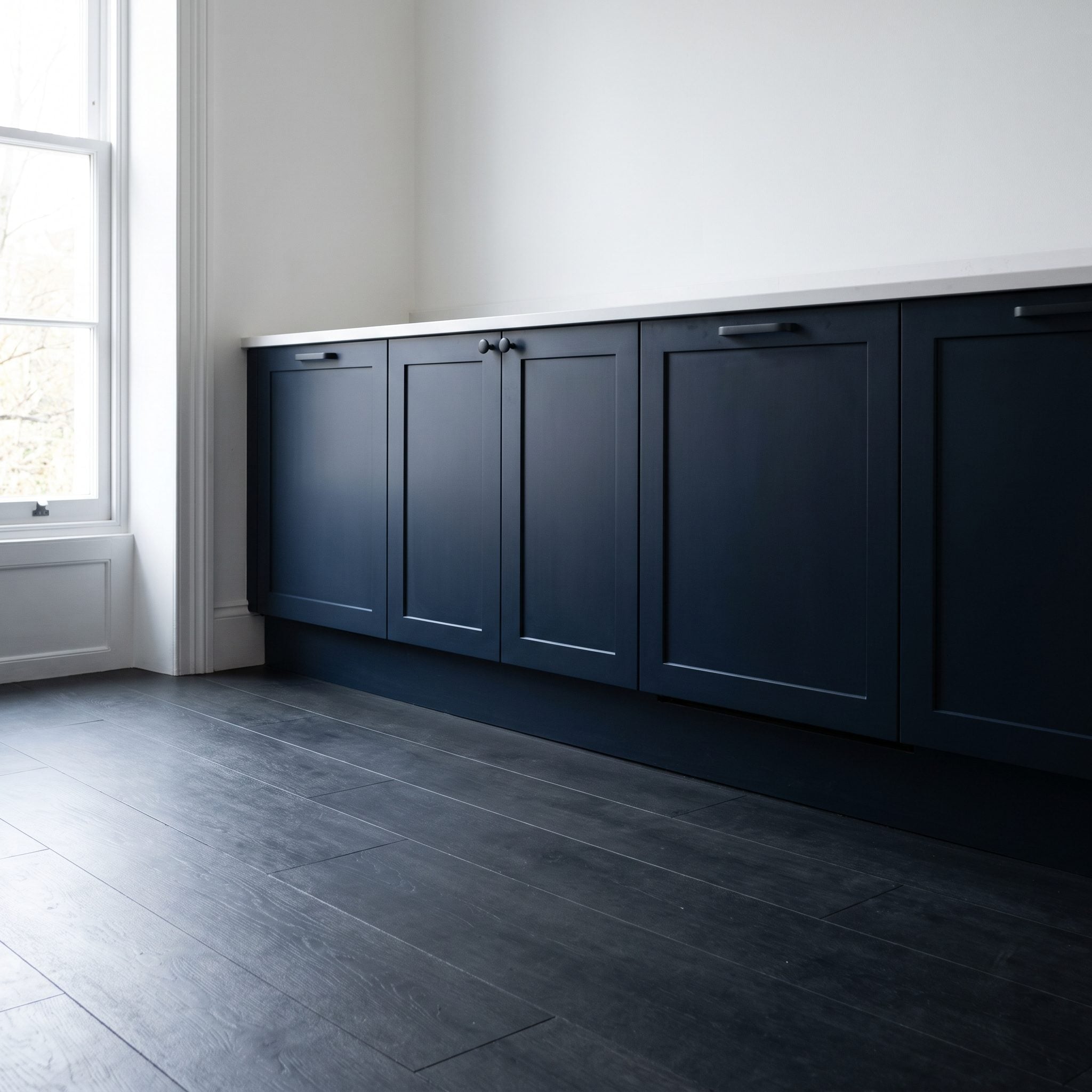 Navy kitchen cabinets with new pale terrazzo-look porcelain flooring replacing dark hardwood