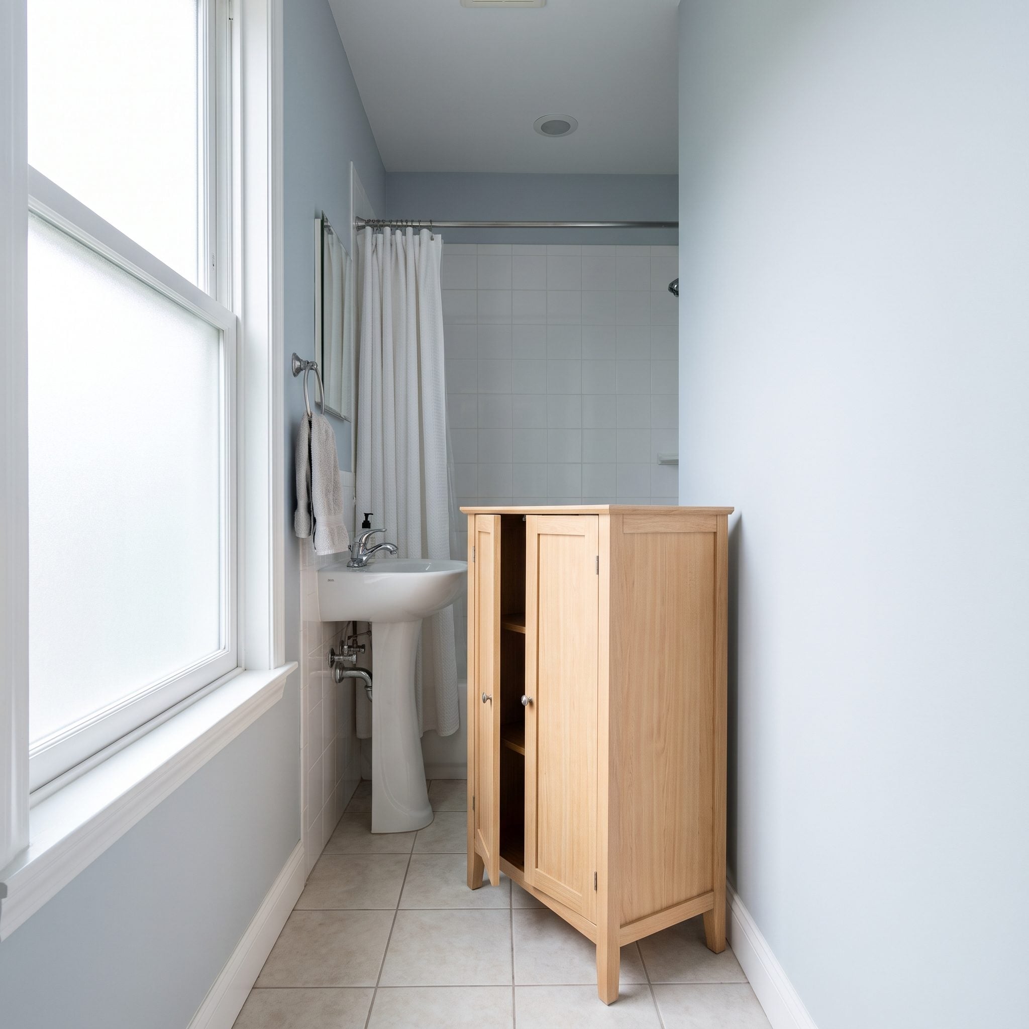 Sage green bathroom with a tall linen cabinet tucked against the perimeter and clear central floor