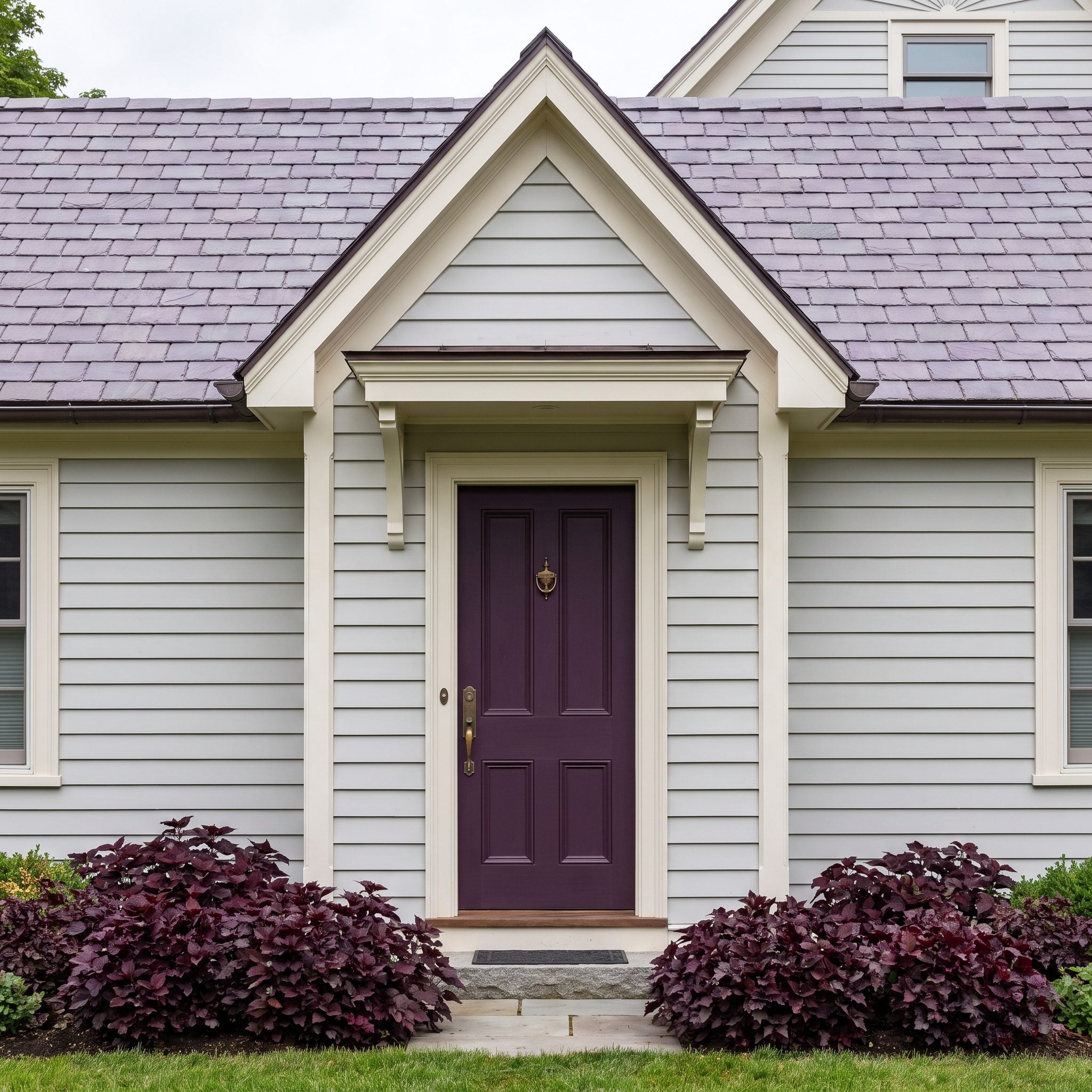 Deep aubergine front door on a Victorian home with silvery-gray siding and slate roofing