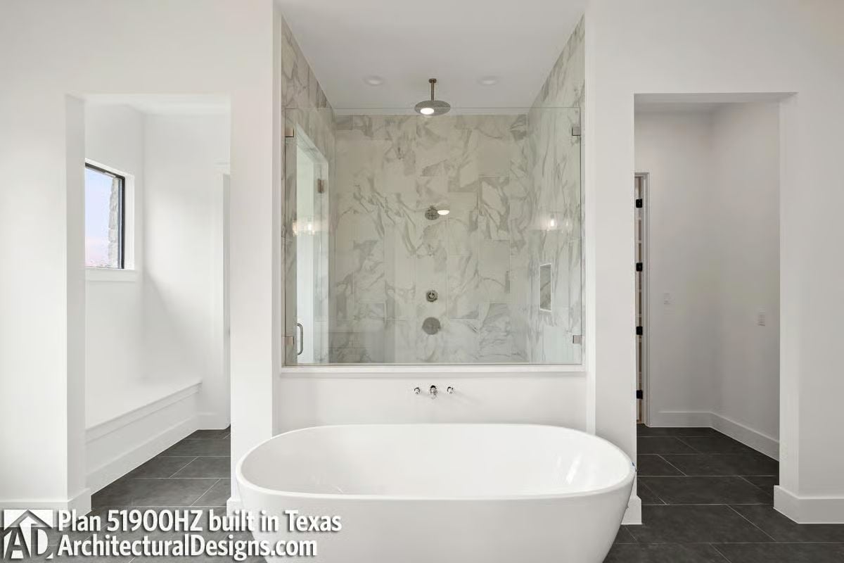 Marble Shower Wall, Freestanding Tub, and a Ceiling-Mount Head Worth Planning Around