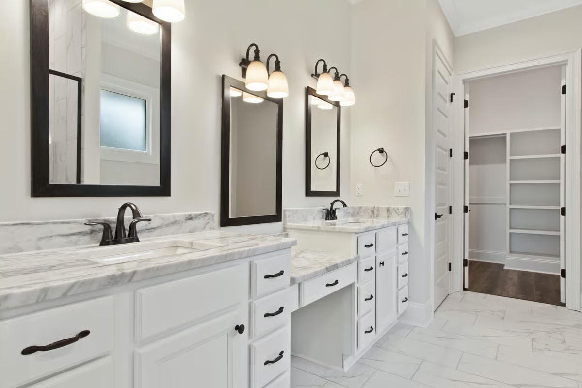 Dual Vanities, Marble Counters, and a Walk-In Closet Visible From Both Sinks