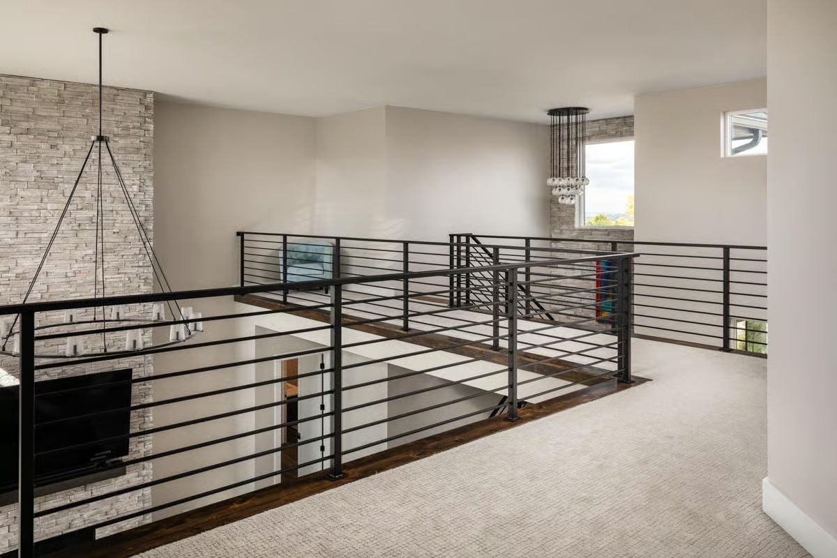 Open Loft Railing in Black Steel Wraps the Stairwell on Three Sides
