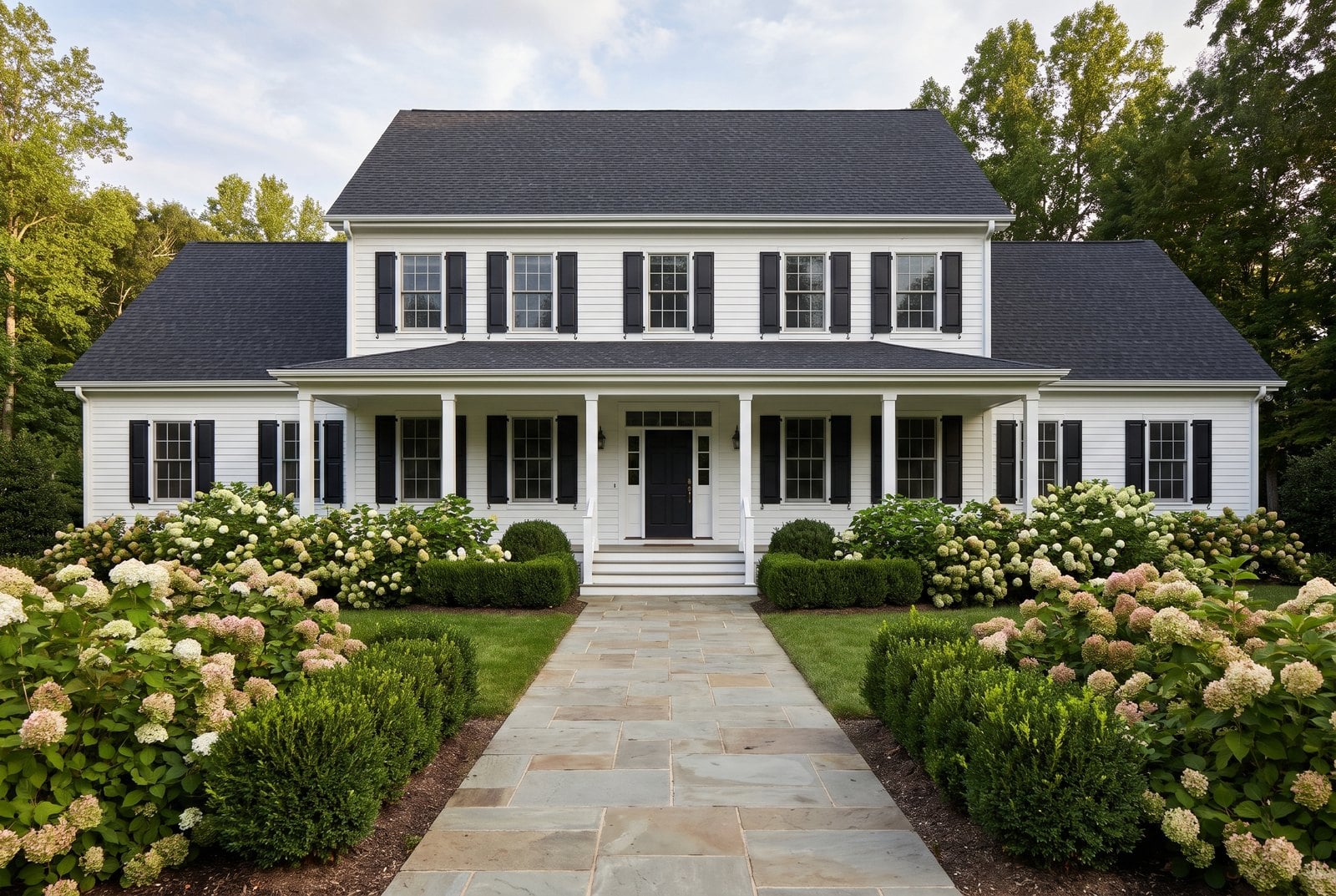 Traditional house with a front porch, dark roof and lush front yard