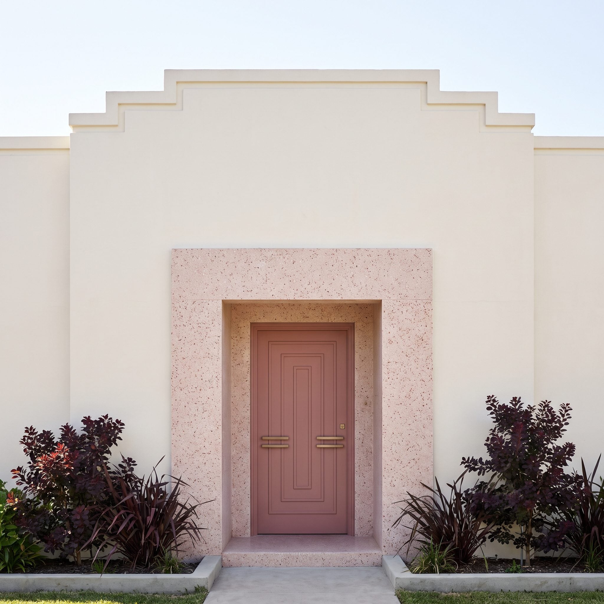 Dusty-rose Art Deco front door with terrazzo paving and pale architectural surround