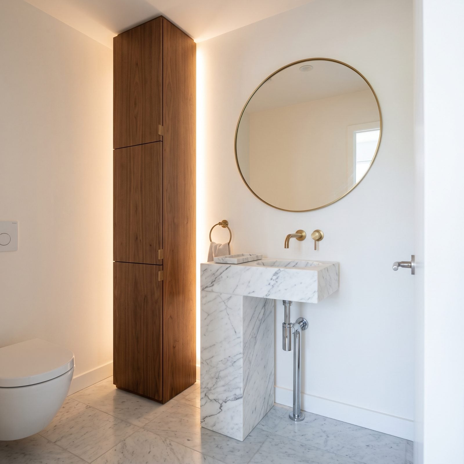 A Freestanding Marble Column Basin Next to a Walnut Storage Tower