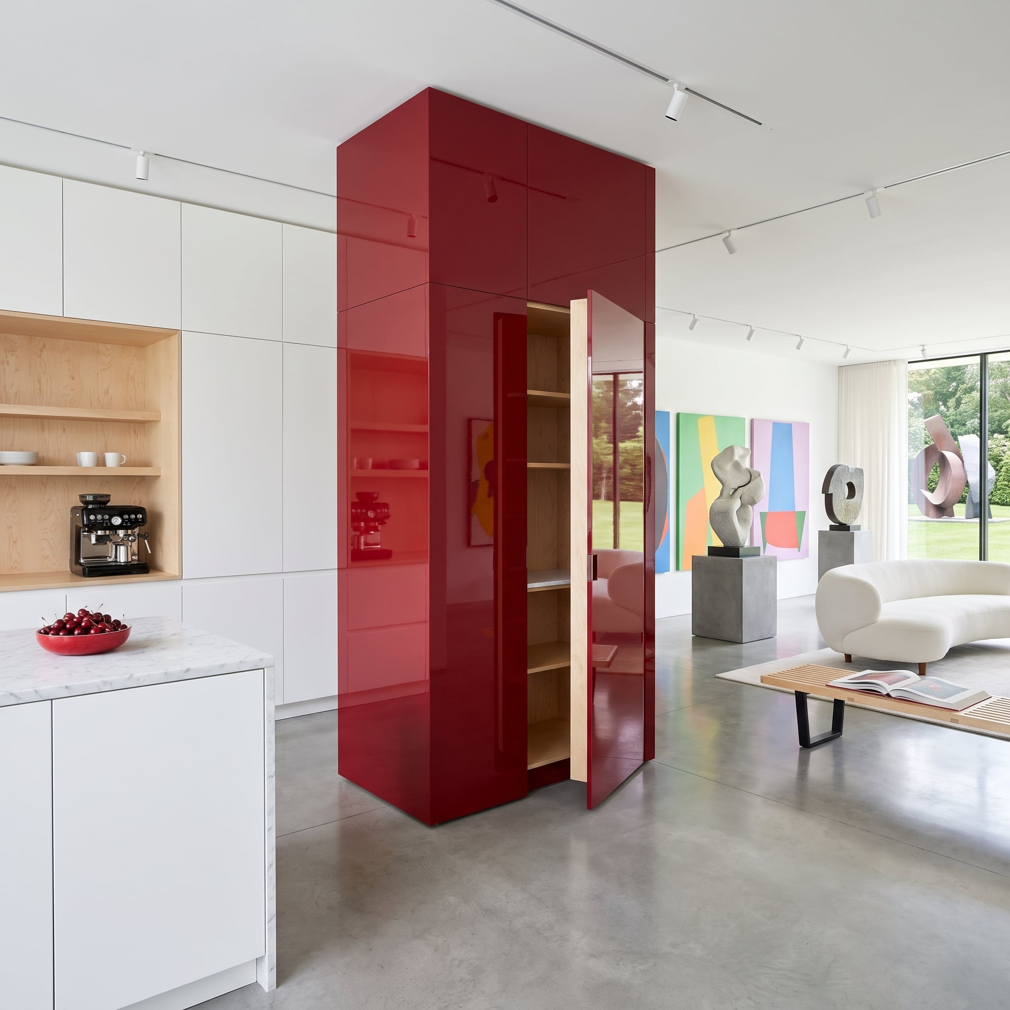 Glossy crimson cabinetry creates a visual boundary in an open contemporary kitchen