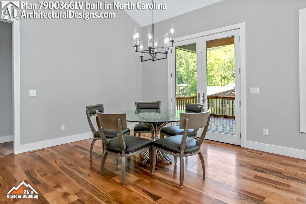 Glass-Top Dining Table Centered Under a Modern Chandelier with Mountain Views Beyond