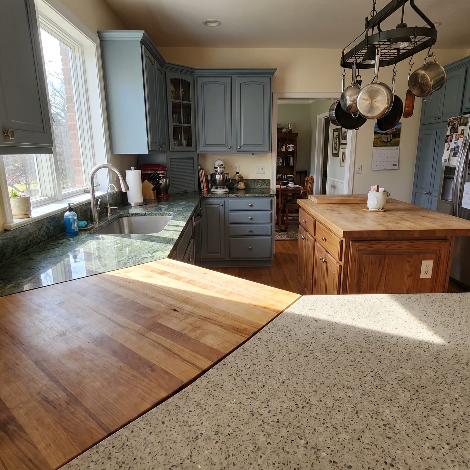 Kitchen showing three different countertop materials: gray granite perimeter, marble island, and butcher-block nook.