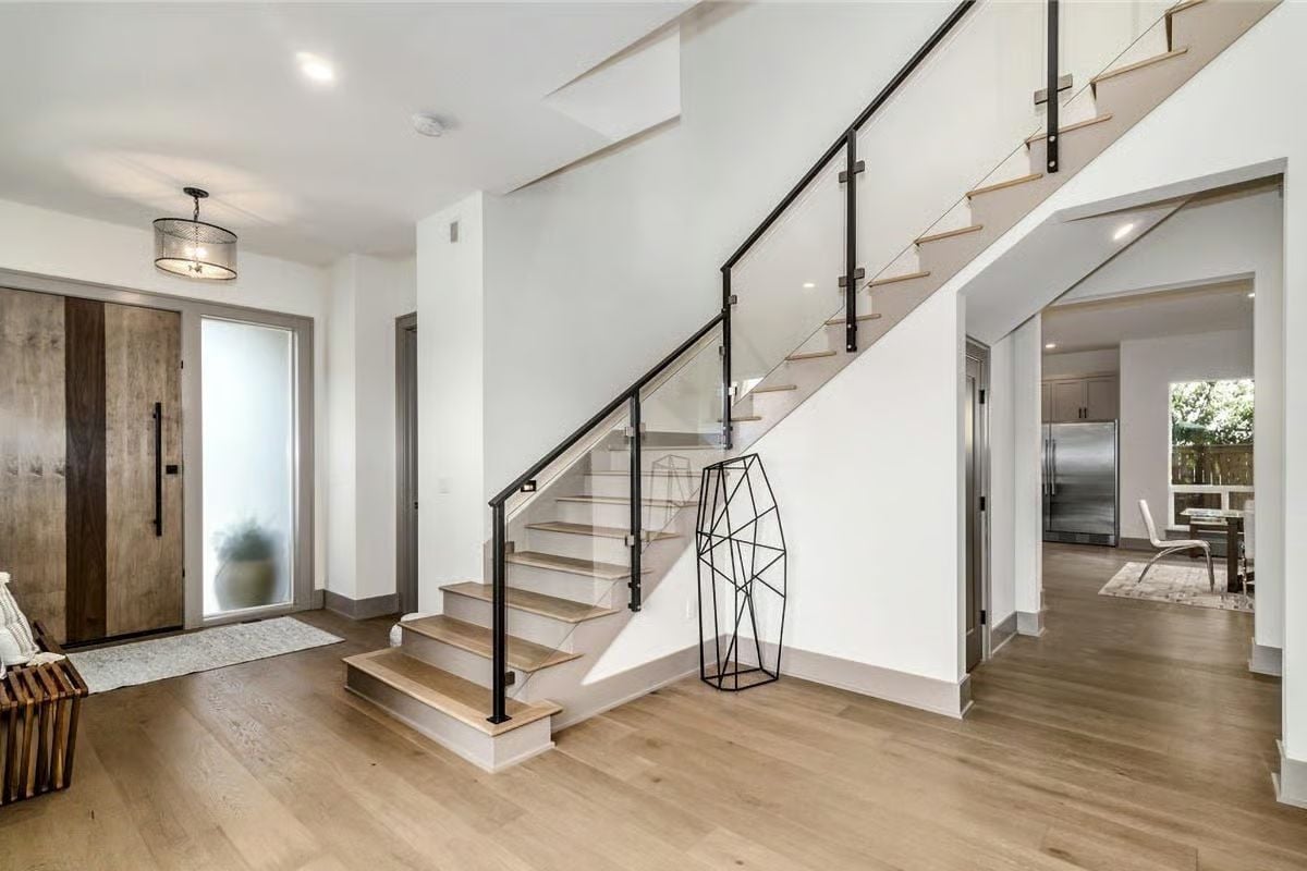 Glass Railings and a Raw Wood Front Door Set the Tone at the Entry