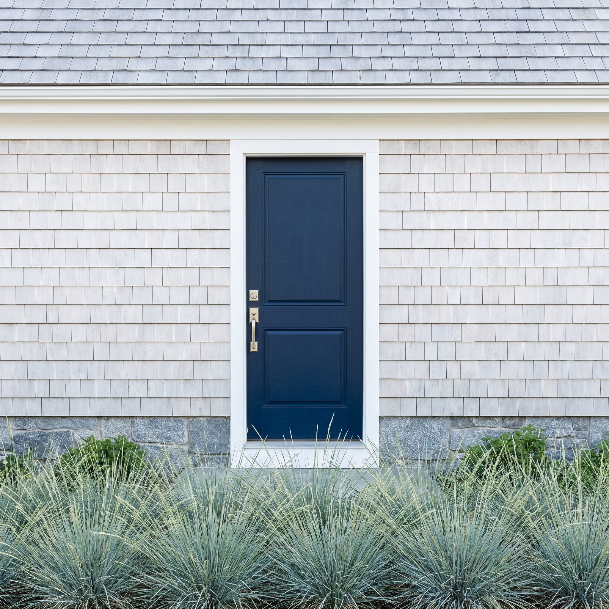 Midnight-navy front door on a light coastal home with a silver-gray roof