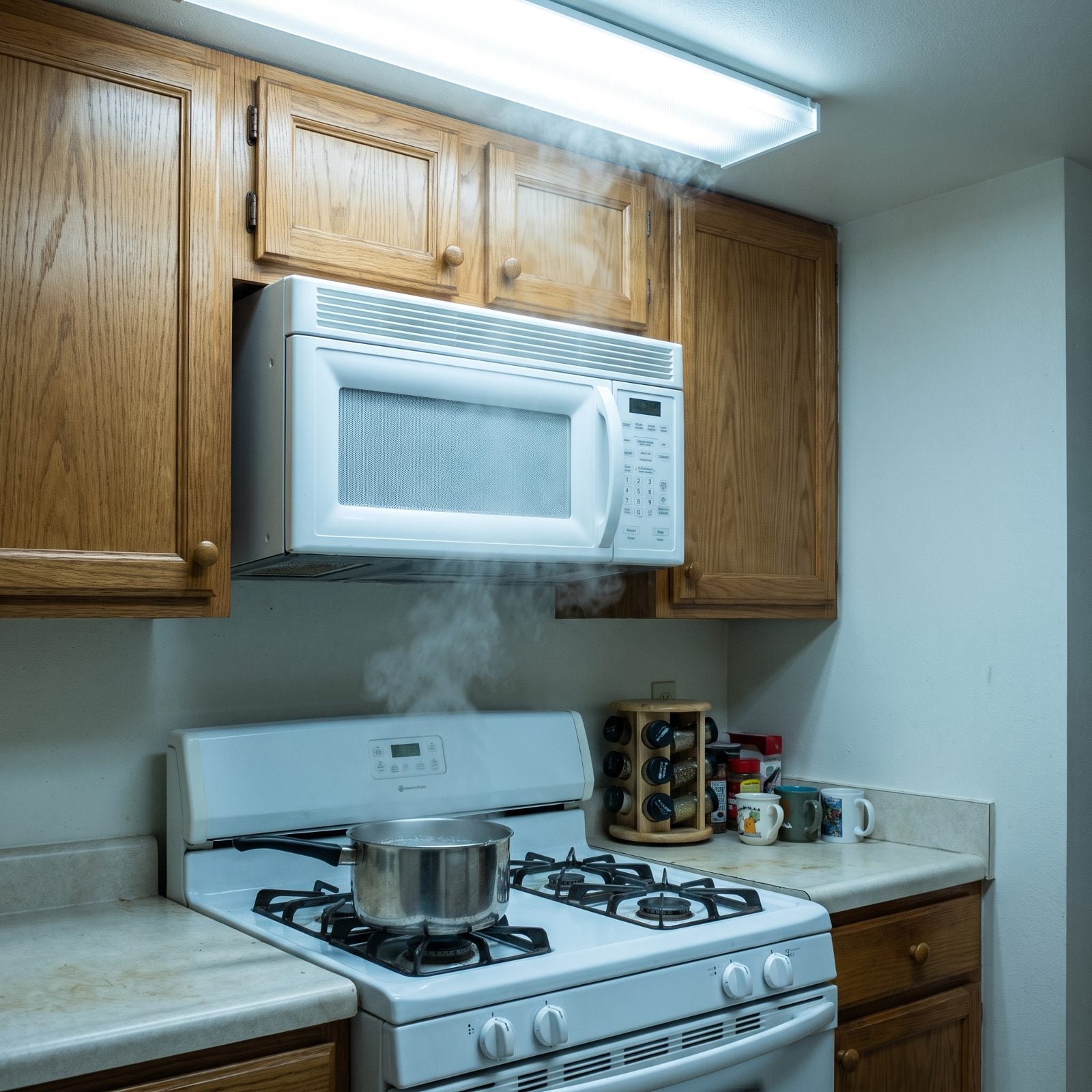 White shaker kitchen with an over-the-range microwave mounted about eighteen inches above the cooktop.