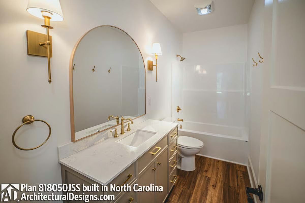 Brass Hardware Doing the Heavy Lifting in an Otherwise All-White Bathroom