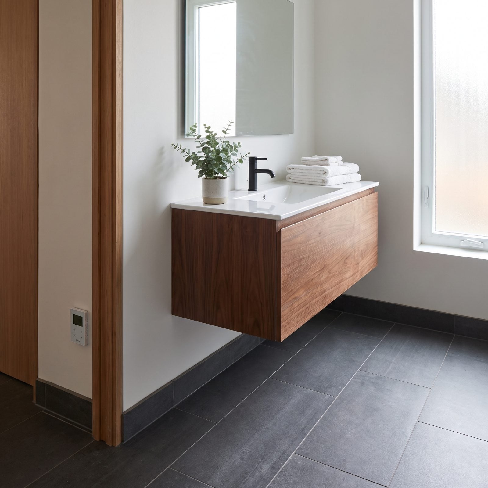 Modern tiled bathroom with embedded radiant floor heat and no visible access panel or junction box for the system.