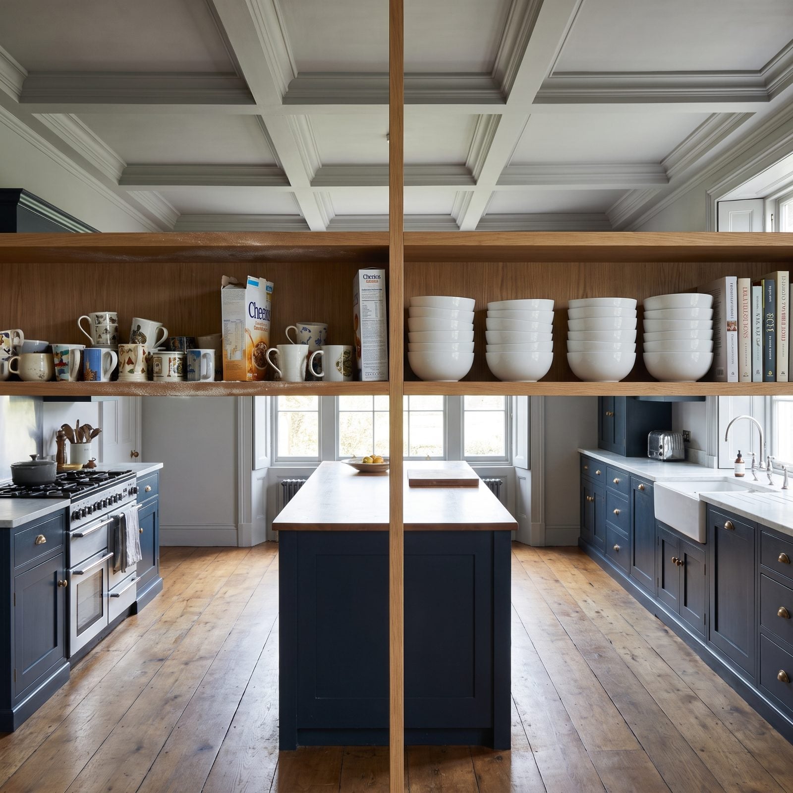 White kitchen with three long open oak shelves holding everyday glasses, cereal, and plates with dust on top.