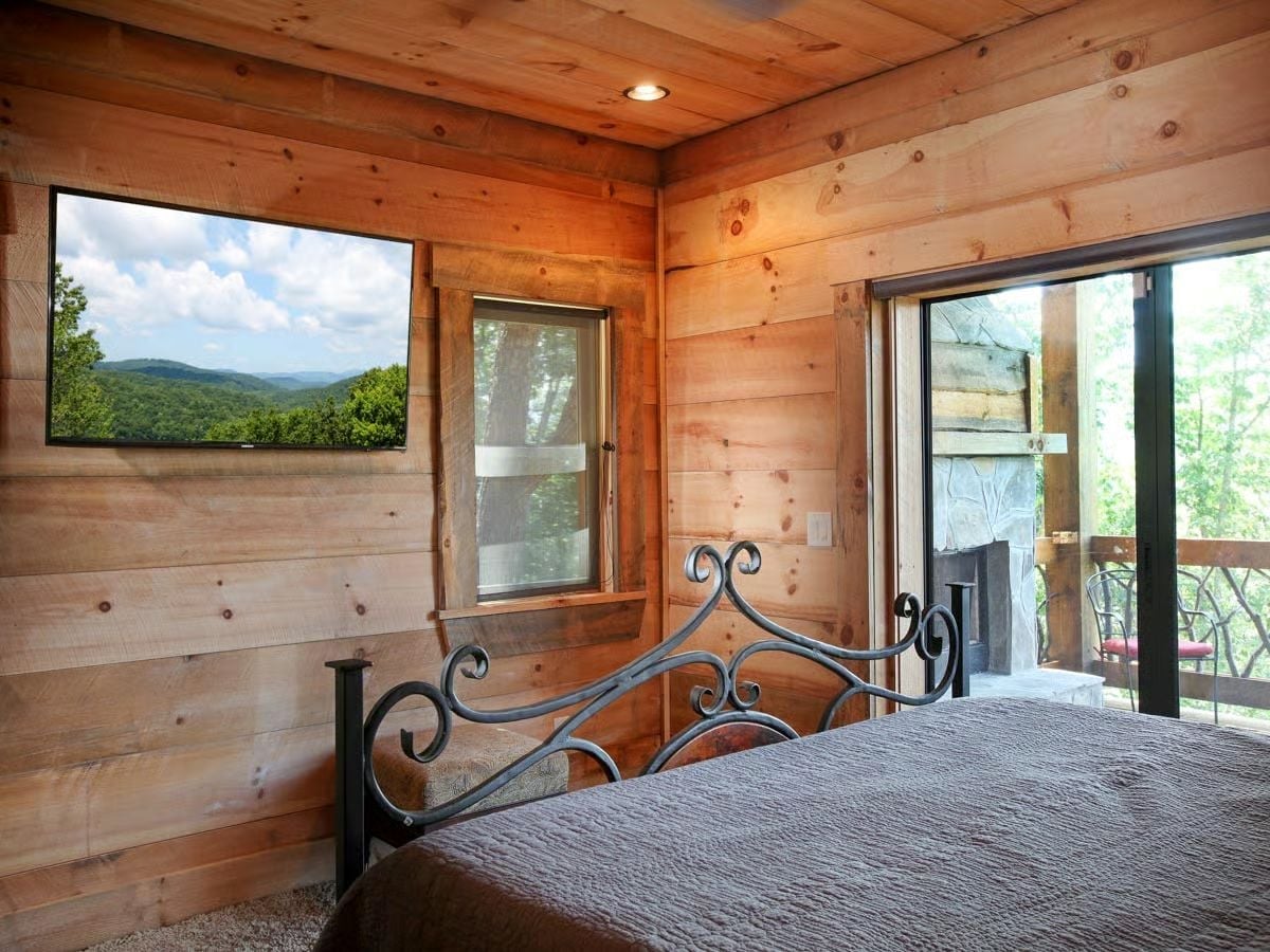 Iron Scrollwork Headboard and Mountain Views Through a Flat-Screen Frame