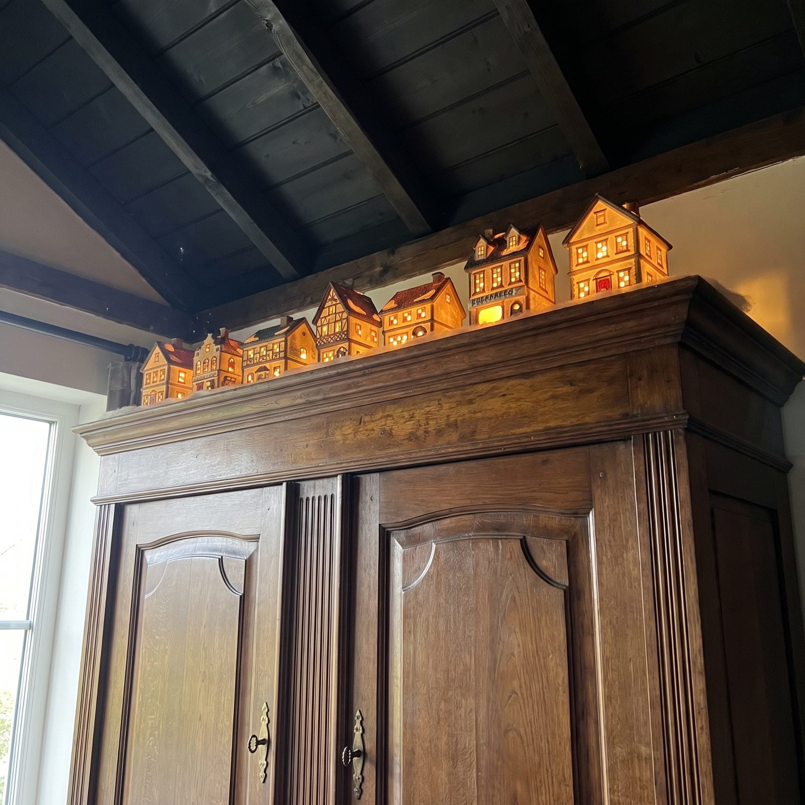 The Top of a Tall Wardrobe, Lined With Glowing Little Houses