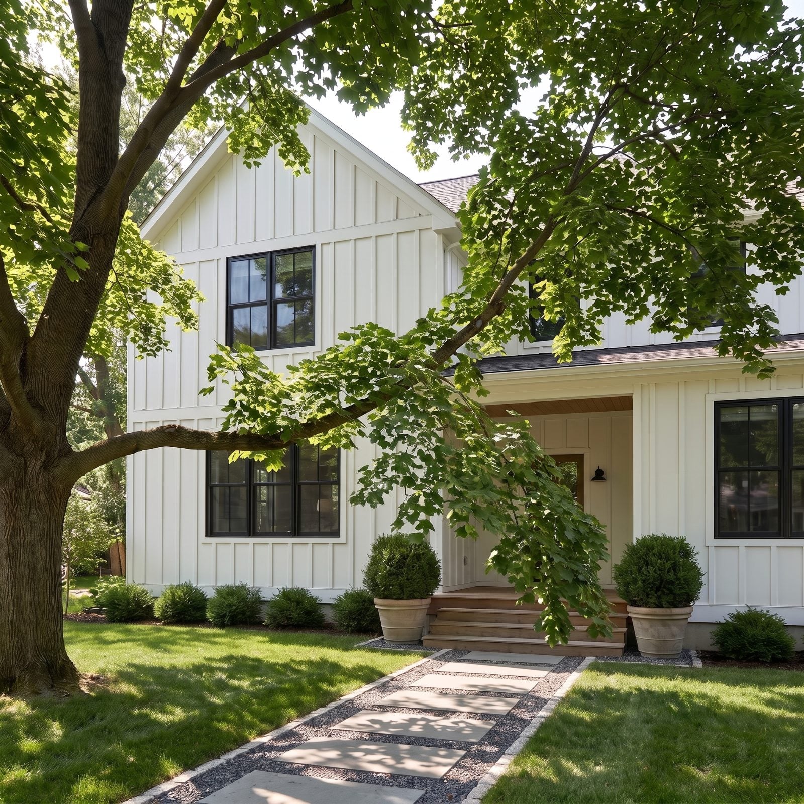 White farmhouse with a maple whose low branches hang across the front path at about head height.