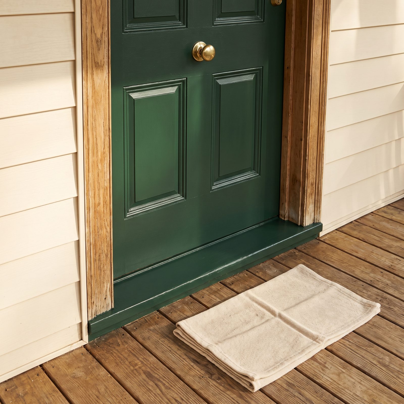Front door close-up showing a freshly painted forest-green door with clean edges and a centered brass handle.