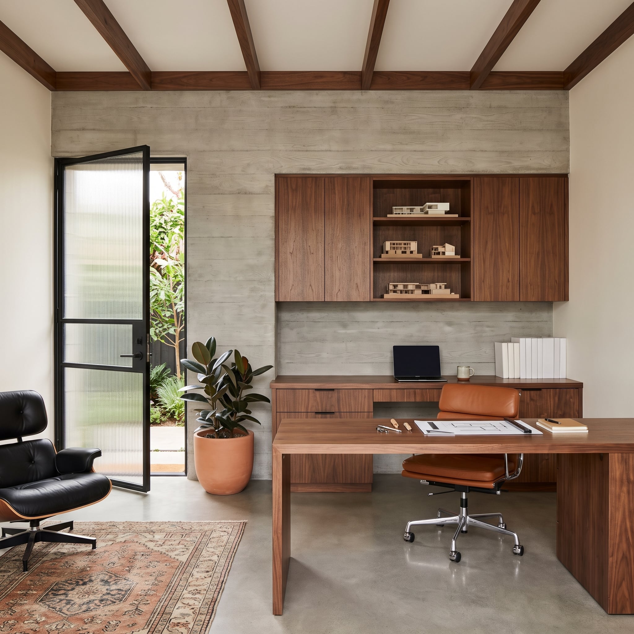 Board-formed concrete office accent wall with walnut millwork and black leather chair
