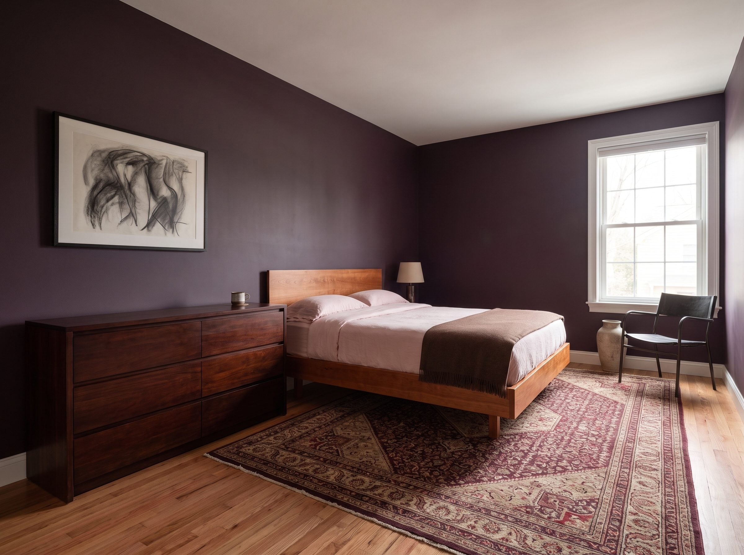 Bedroom with deep plum walls, a honey-toned platform bed, dark walnut dresser, and patterned rug
